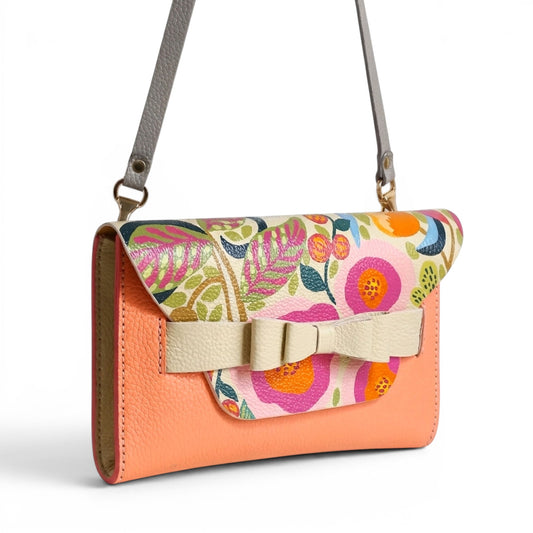 Floral-patterned leather clutch with a bow and shoulder strap