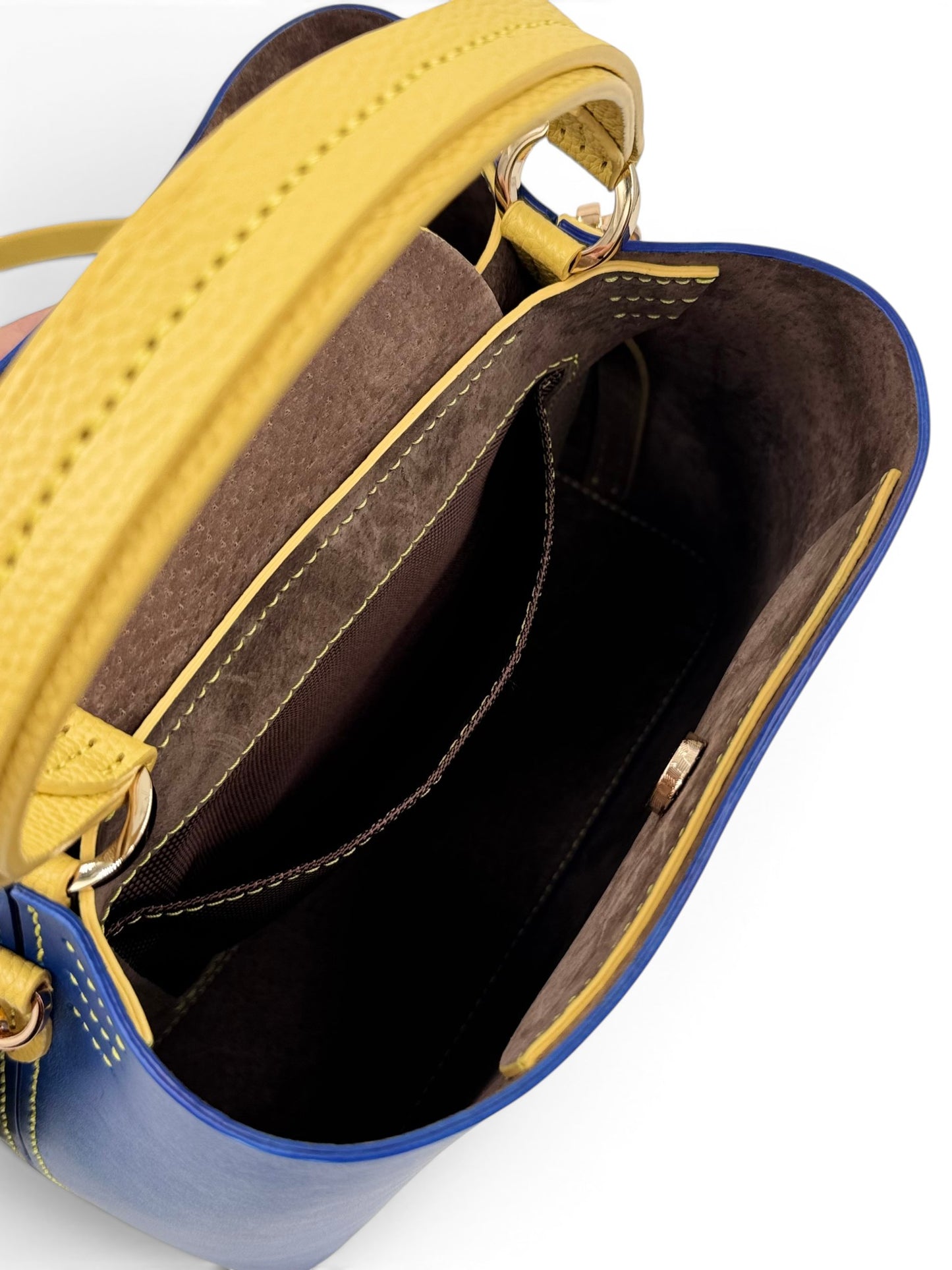 Close-up of a blue and yellow leather handbag with open top, showing interior.