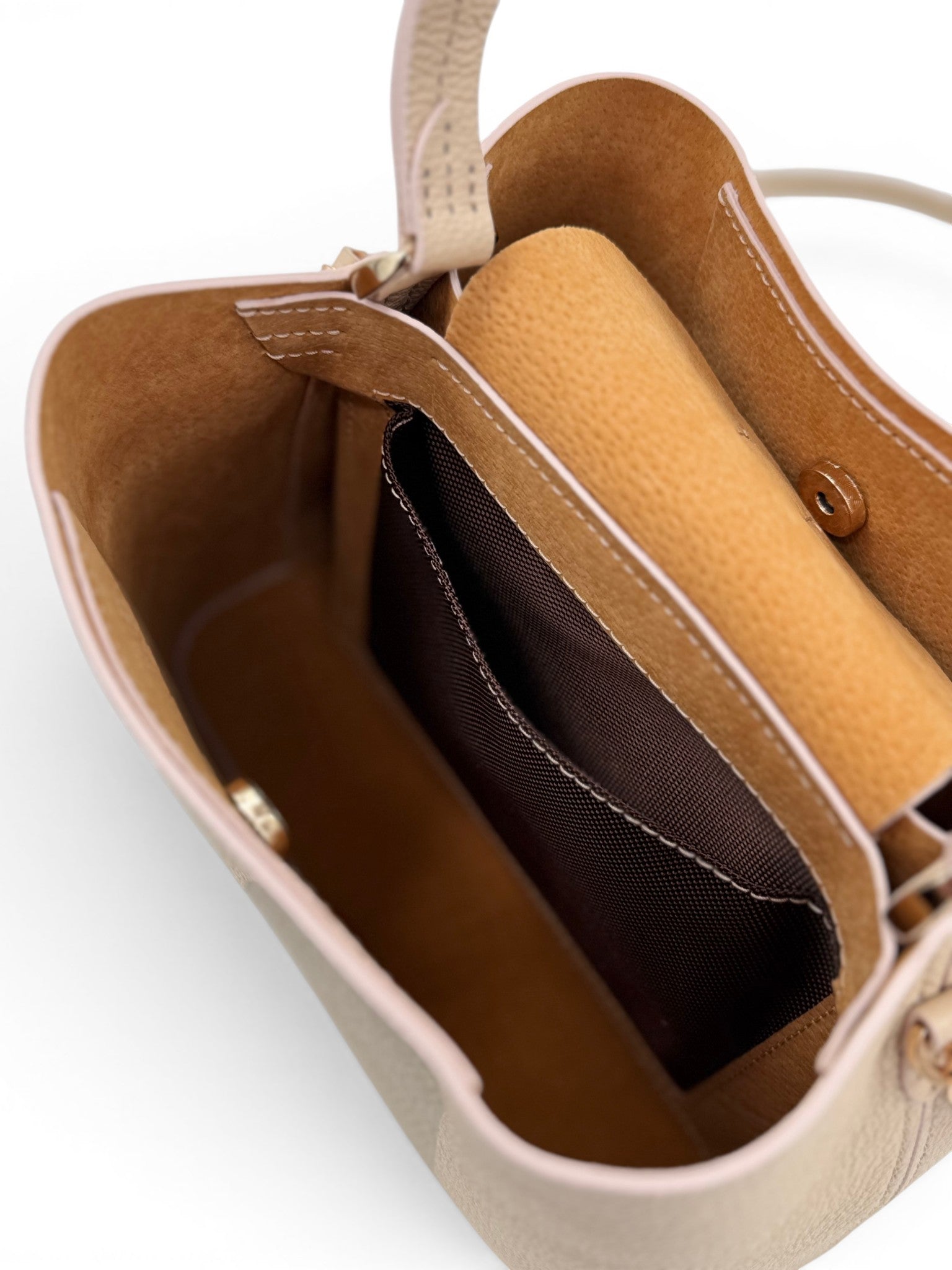 Close-up of a cream leather handbag with a beige interior.