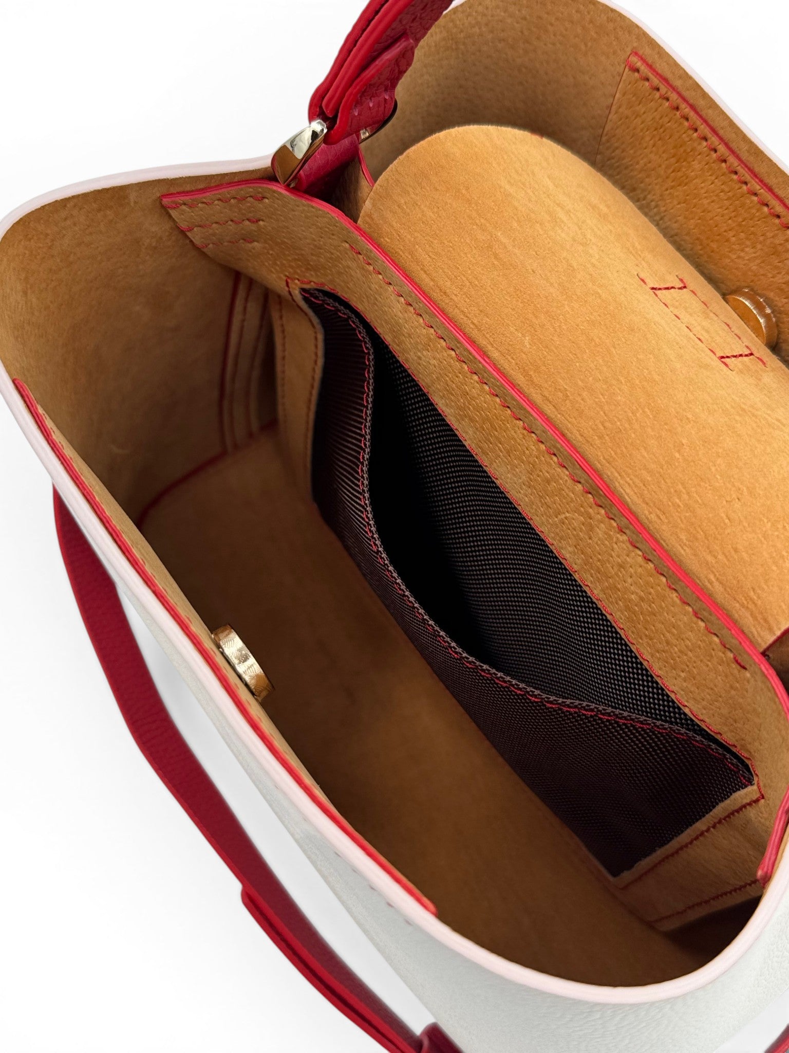Close-up of a White and red leather handbag with visible stitching showing the interior of the bag