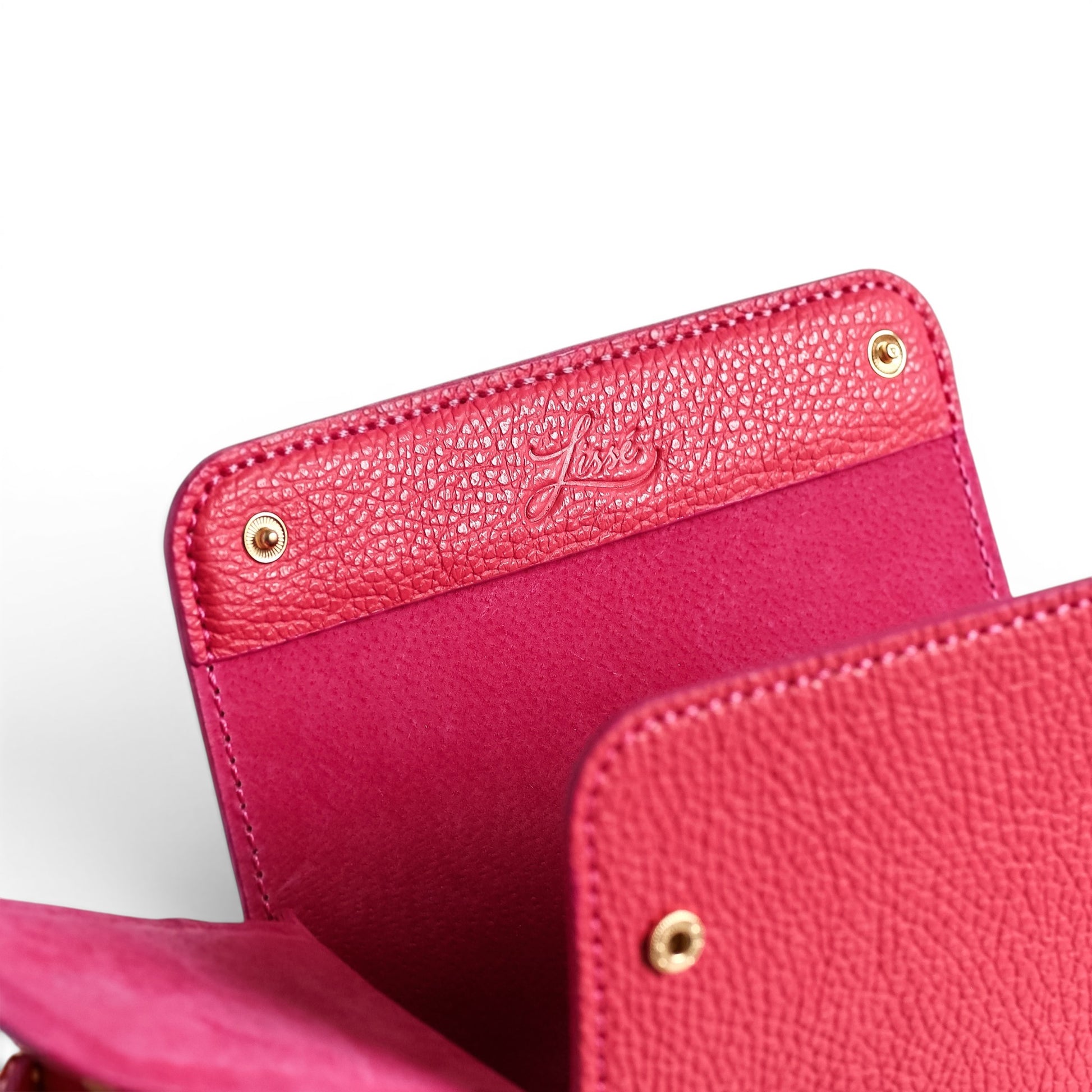 Close-up of a coral leather crossbody bag with golden harware