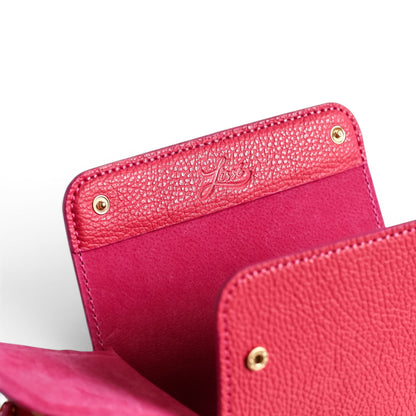 Close-up of a coral leather crossbody bag with golden harware